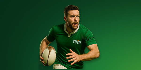 Rugbyspeler in groene shirt met bal in de hand kijkt gefocust vooruit