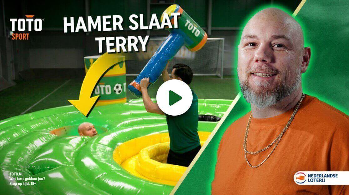 Persoon slaat met TOTO hamer op een opblaasbarrière met daaronder een andere persoon