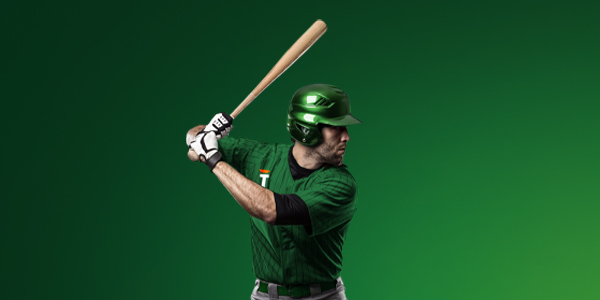 Honkballer in groene outfit van TOTO klaar om de bal te slaan tegen groene achtergrond